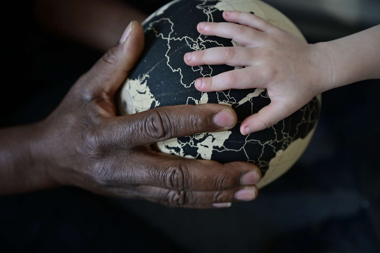 En voksen og en barnehånd der holder en globus